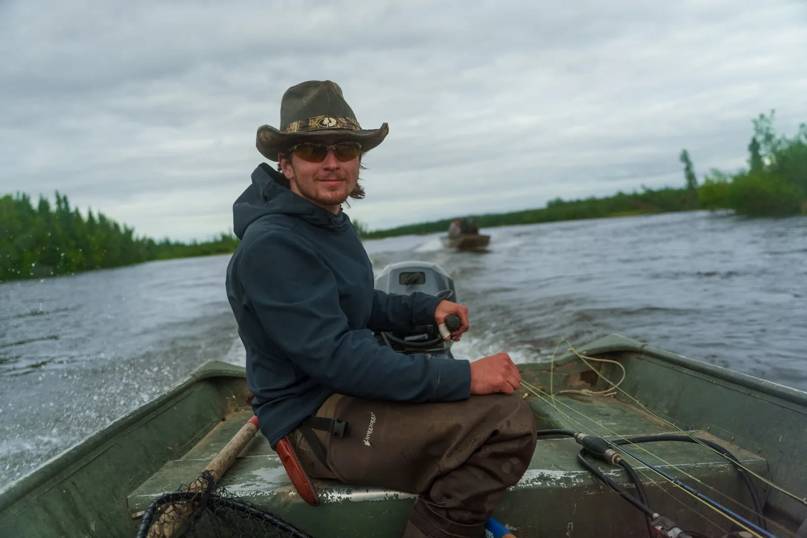 Guide in a wide-brim hat running the boat down the river
