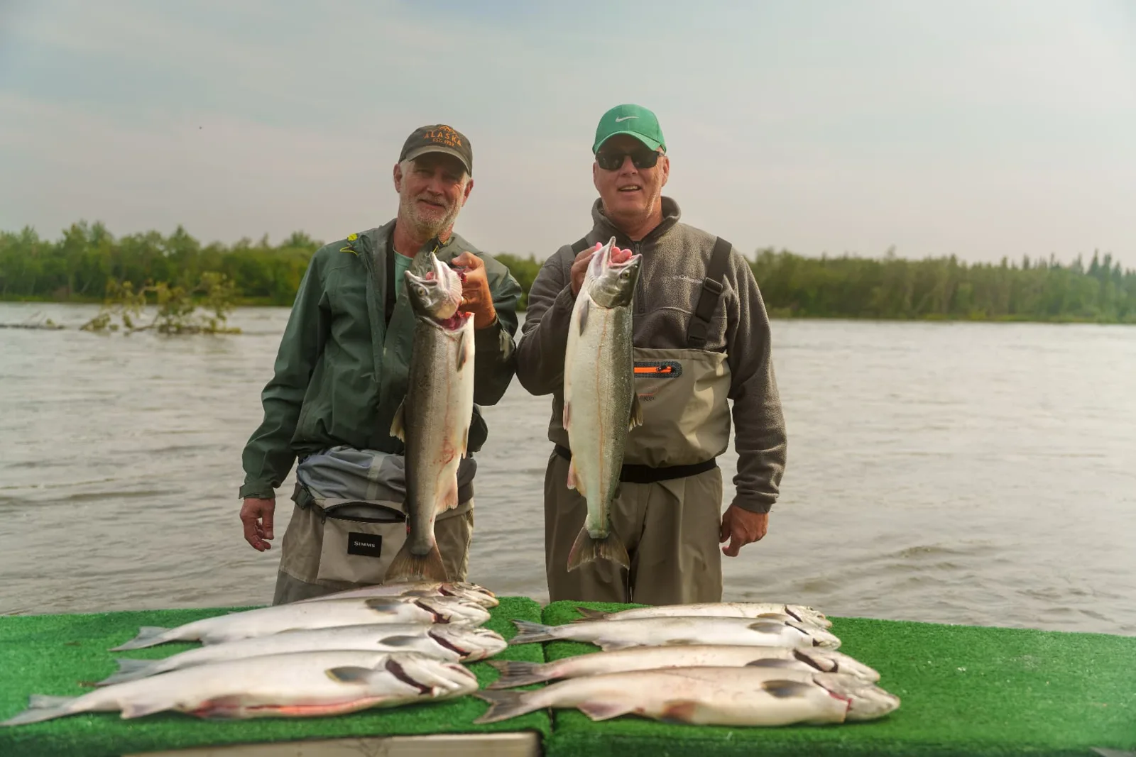 Two guests holding silver salmon beside the day's catch