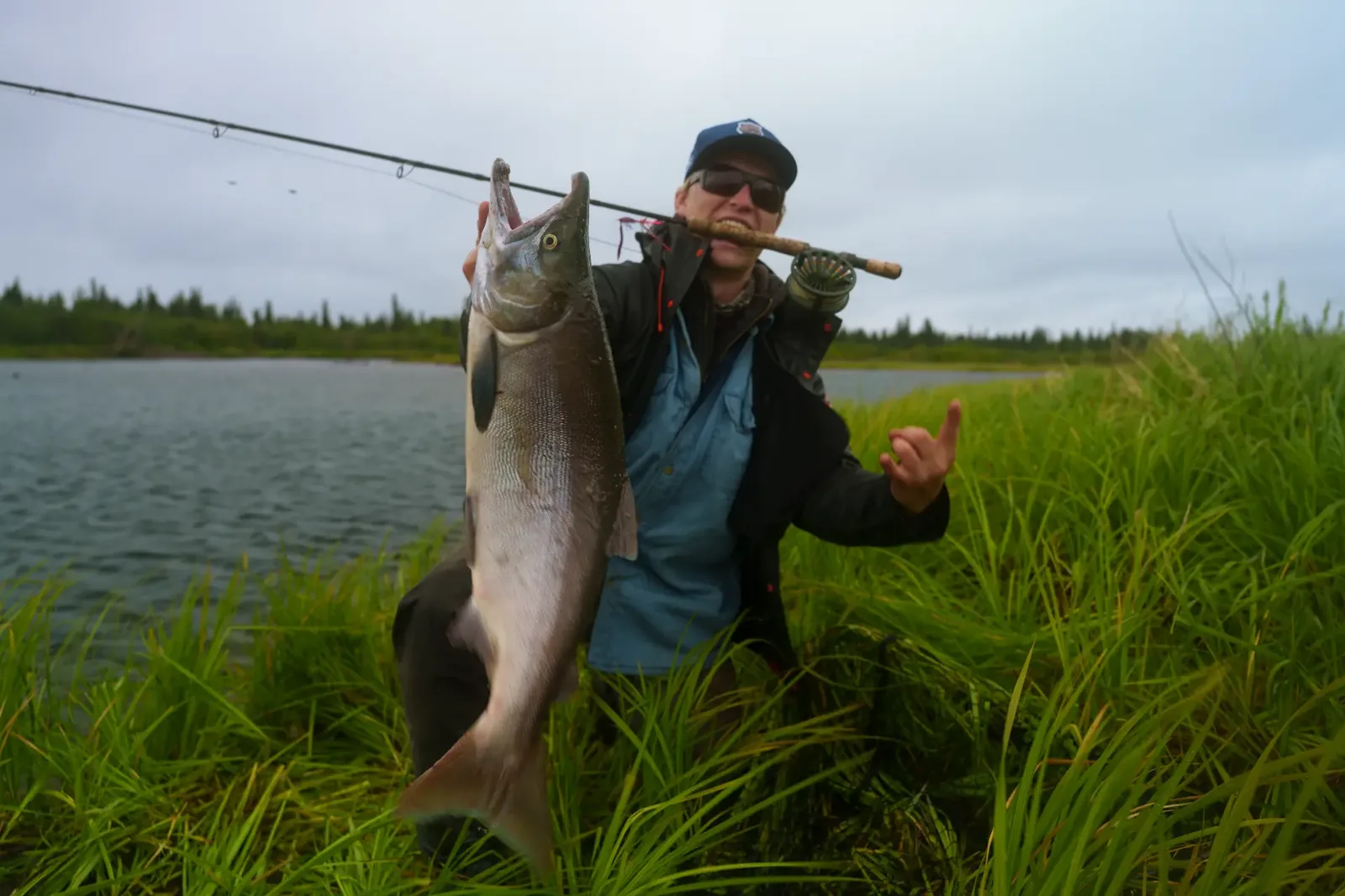 Angler holding a large sockeye salmon beside an Alaska river